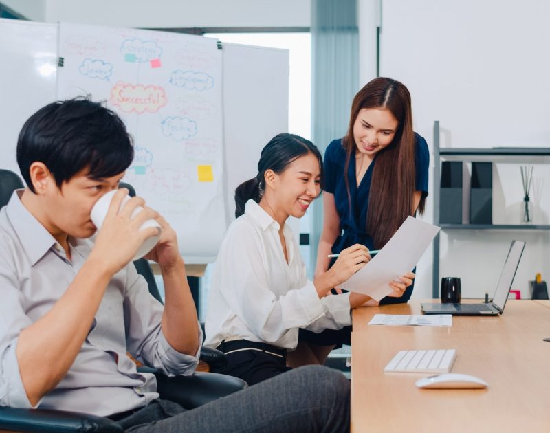 Collaborative process group of multicultural business people in smart casual wear communicating and using technology while working together in creative office. Asia team of young professionals work.